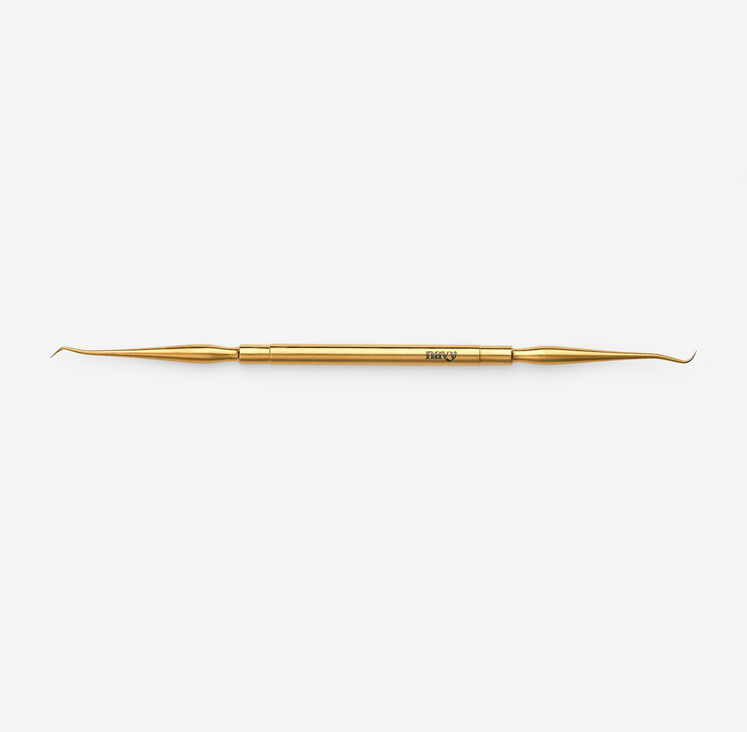 A double-ended lash lifting tool, gold in color