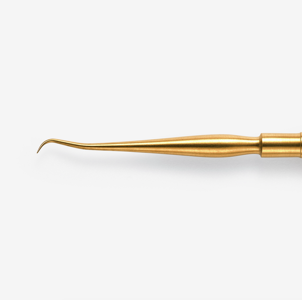 A double-ended lash lifting tool, gold in color