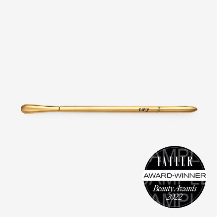 Gold curved manicure tool for nail prep.