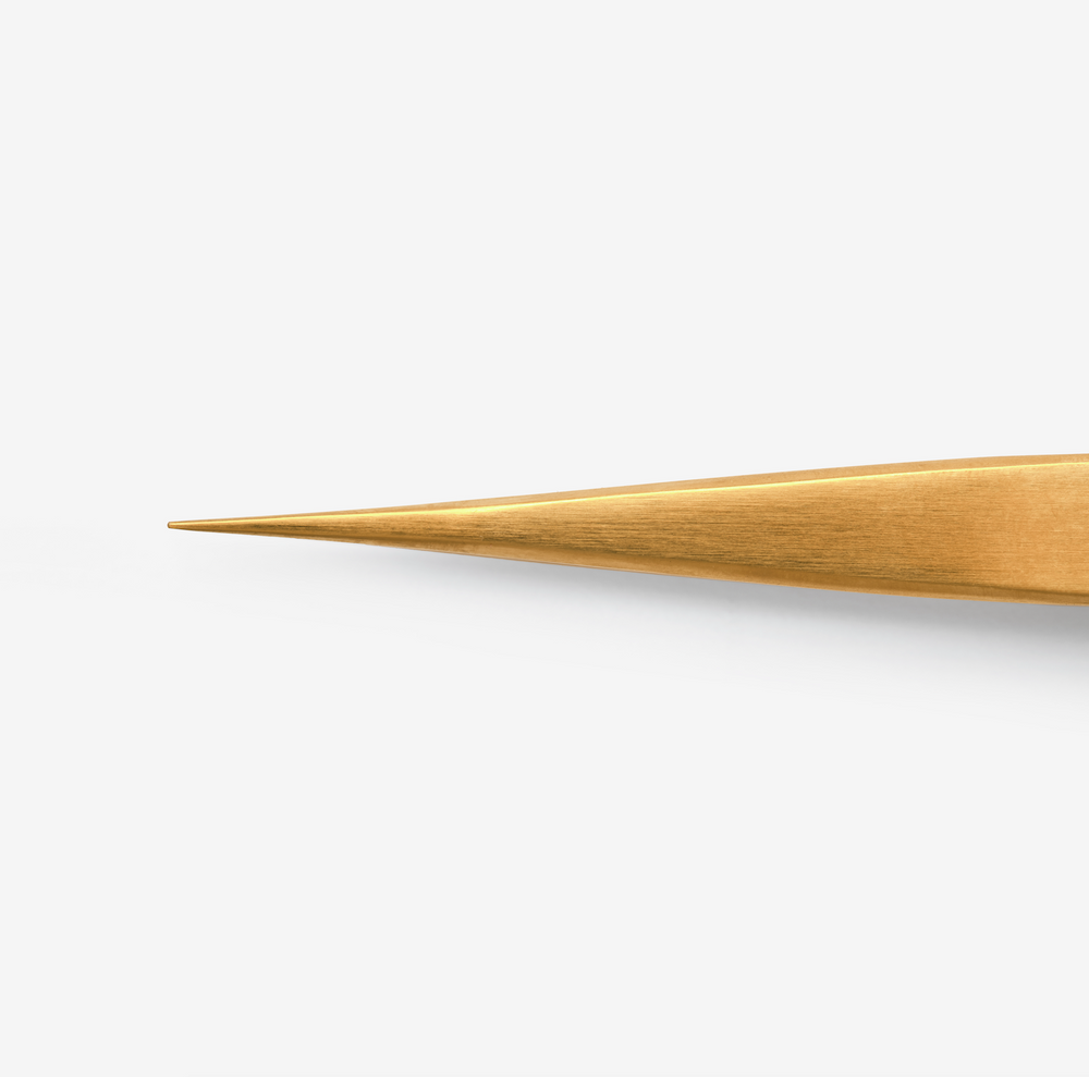 A single gold-coloured-coated tweezer with a pointed tip, against a white background close up