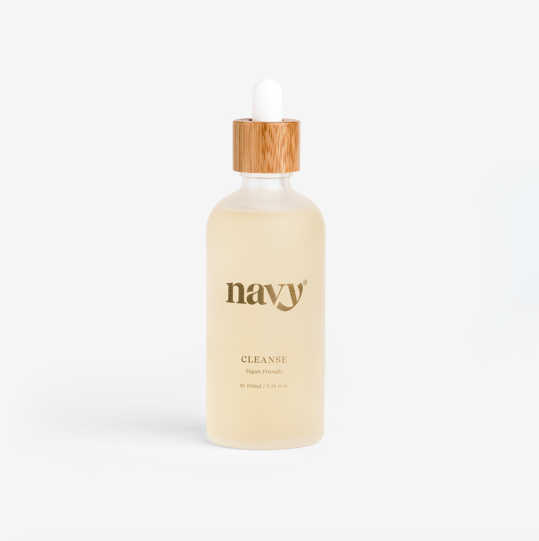A clear glass bottle with a dropper filled with yellow liquid, labeled 'navy CLEANSE', with a wooden cap. Soak for hands and feet.
