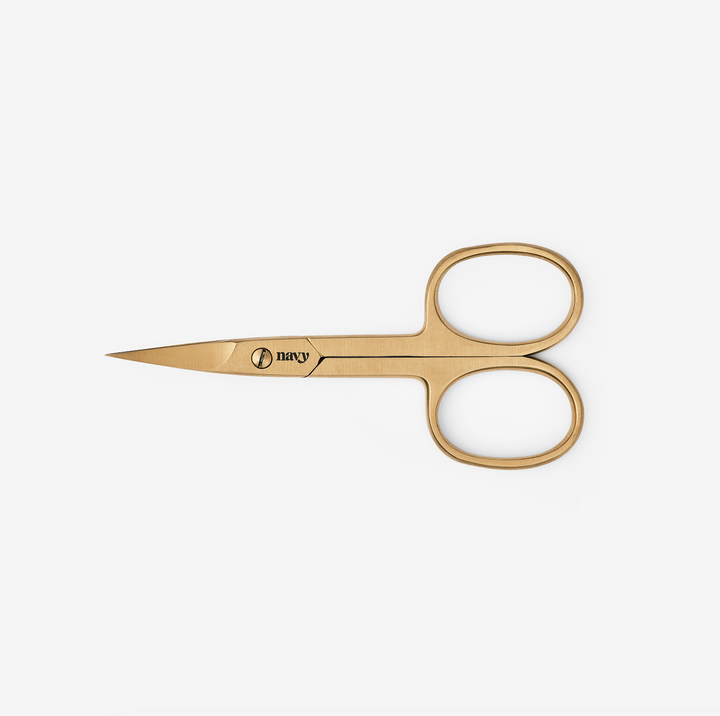 A pair of gold-coloured, curved professional manicure scissors with the brand name 'Navy' visible on the blade.