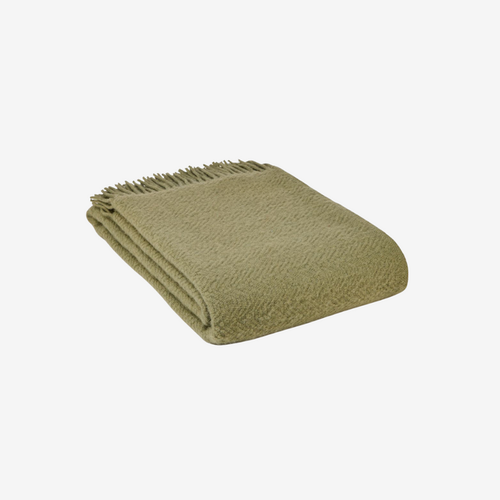 Folded green blanket on a white background