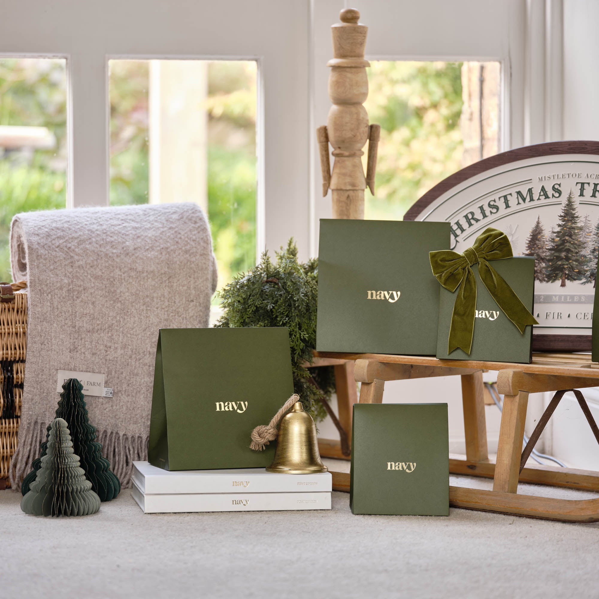 Green gift boxes with 'navy' text on a table in a room with a Christmas-themed tablecloth.