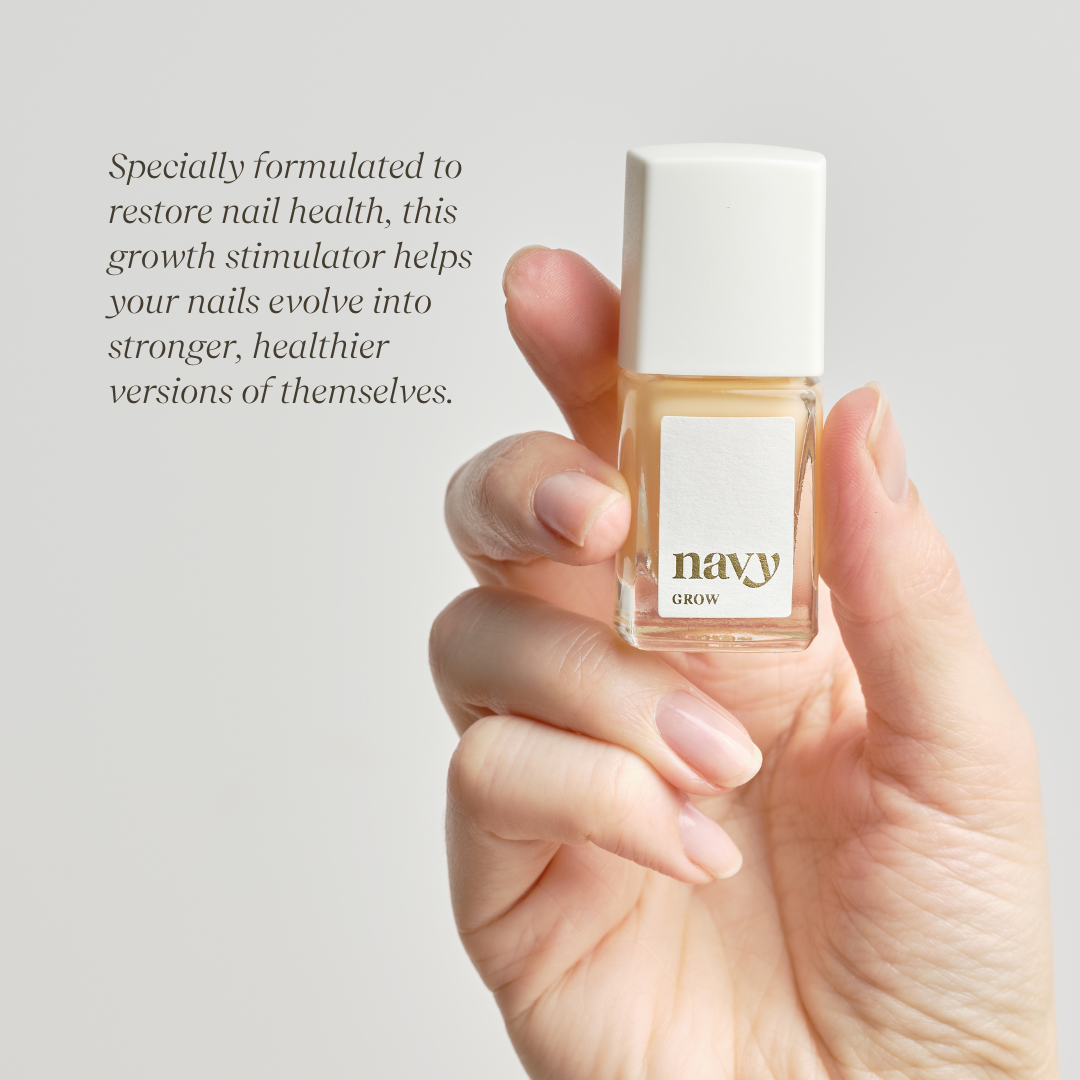 A nail growth treatment bottle held in a hand with bare nails with the brand name 'navy' displayed the bottle giving information on how it stimulates growth