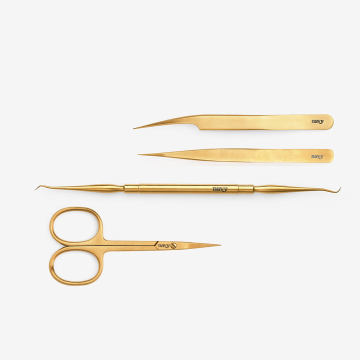 A set of gold-colored eyelash application tools including a double-ended multi tool, straight scissors, straight tweeze, and isolation tweeze.