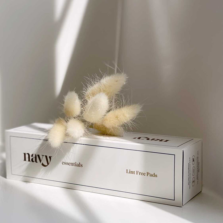 Box of 'navy essentials' lint free pads with dried pampas grass on a neutral background