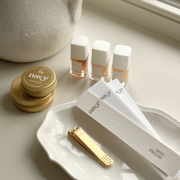 Set of nail care products including a nail file, cuticle pusher, and small bottles on a light surface.