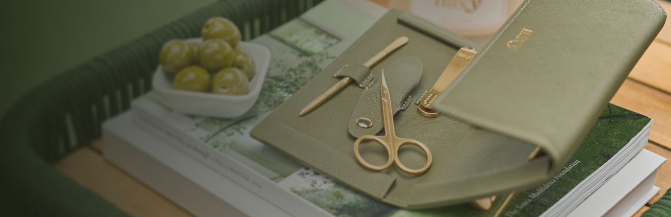 Green notebook with gold scissors and pen on a wooden surface