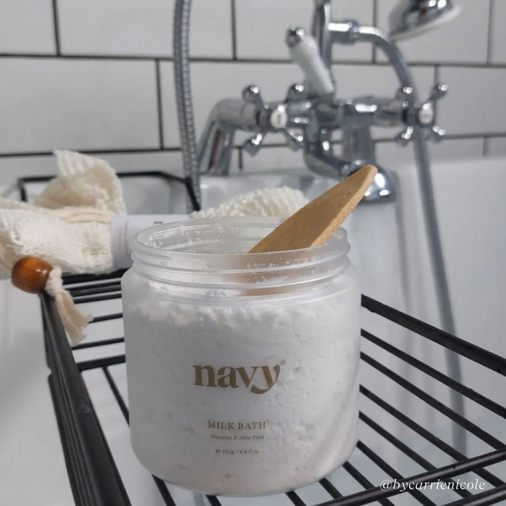Navy Bath Milk in the Bath with bamboo scoop in the tub.