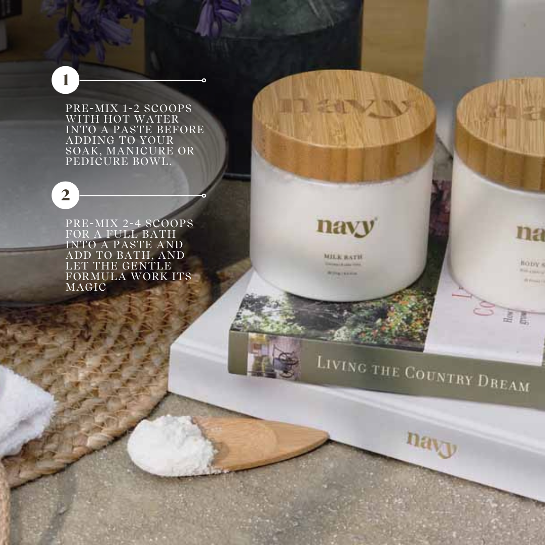 Navy Bath Milk stacked on books.
1) Pre-mix 1-2 scoops with hot water into a paste before adding to your soak, manicure or pedicure bowl. 
2) Pre-mix 2-4 scoops for a full bath into a paste and add to bath, and let the gentle formula work its magic. 