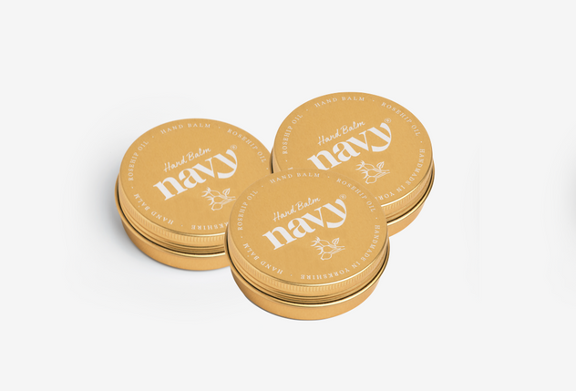 Three round tins of Navy Hand Balm placed together with lids on, against a white background.