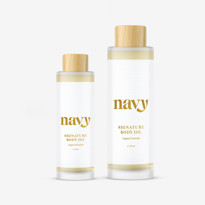  Navy Signature Body Oil, one larger and one smaller, with white labels and gold text, containing natural seed oils for hydration.