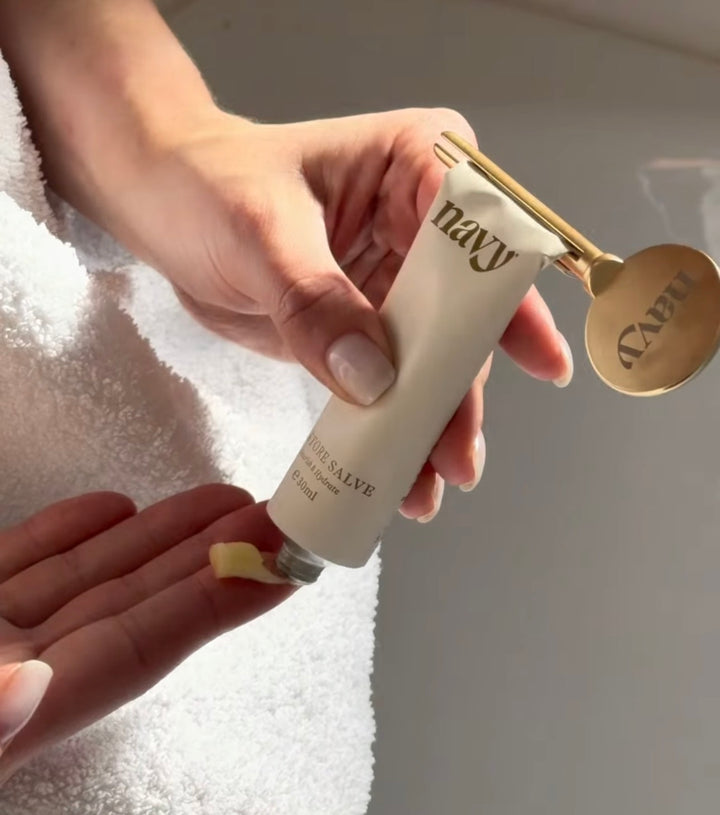 Hand applying a cream from a 'navy' branded tube onto another hand.