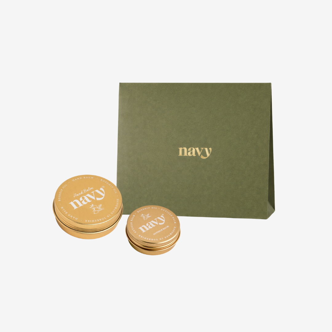 Two gold tins with 'navy' branding next to a green box also labeled 'navy' on a white background.