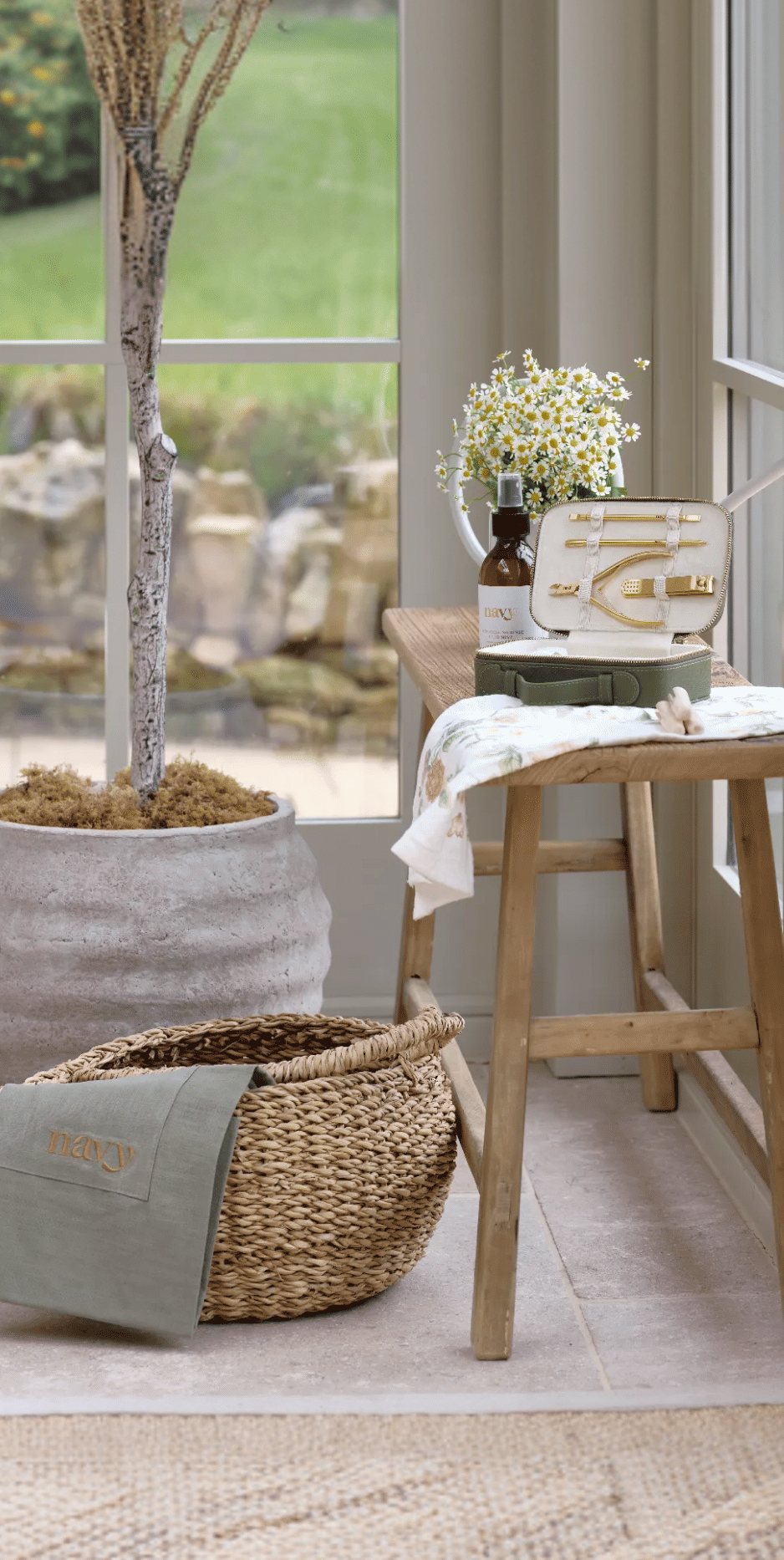 Nestled sunroom with a large window, wooden stool, and decorative plants.