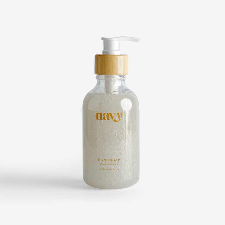 A clear pump bottle with Navy branding containing exfoliating hand soap with fine grains visible in the liquid.