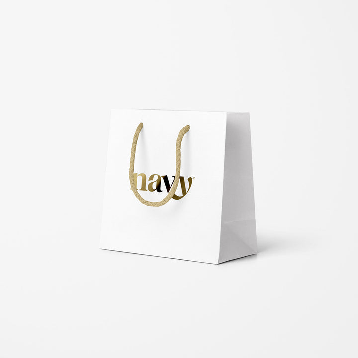 A white gift bag with a gold rope handle and the brand name 'Navy' printed in gold on the front.