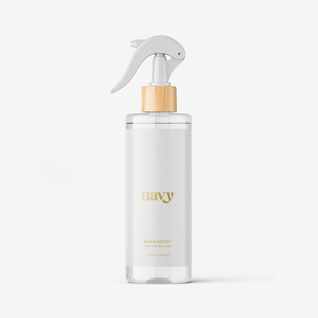 A white spray bottle with a gold label that reads 'navy' and has a wooden spray nozzle. The background is white and clean.