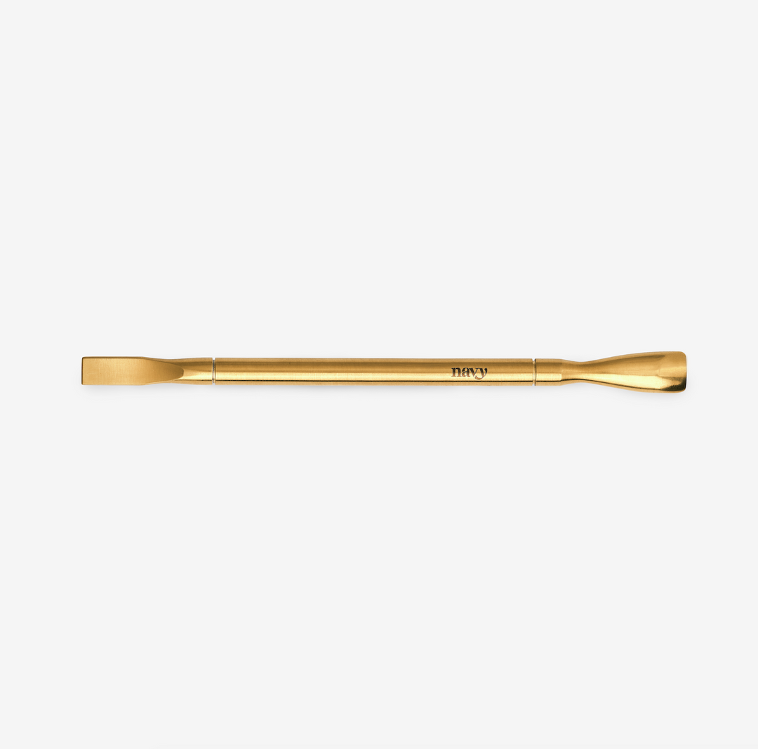 A gold-colored nail removal tool. Designed for the removal of gel and acrylic nail products.