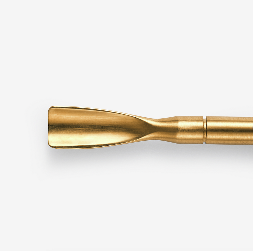 A gold-colored nail removal tool. Designed for the removal of gel and acrylic nail products.