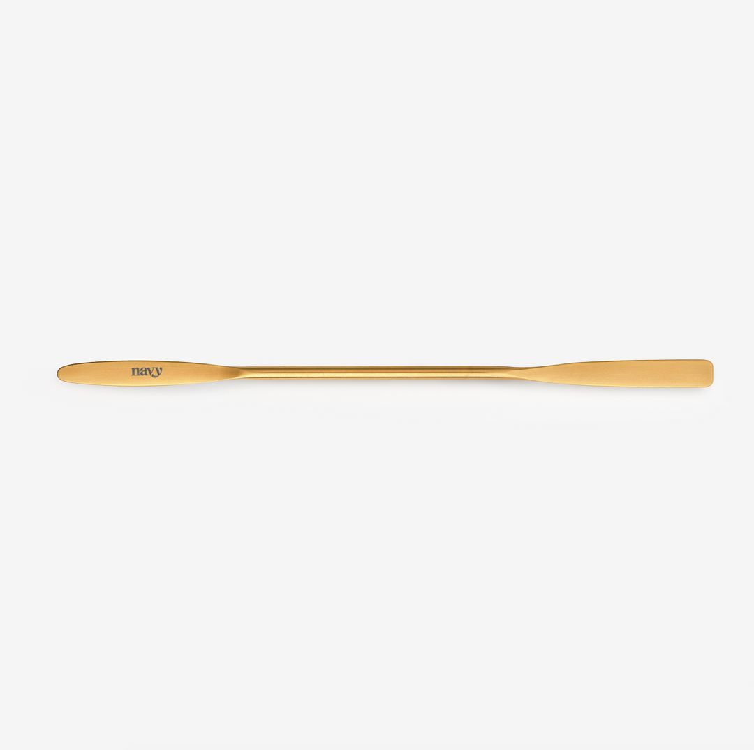 A gold-colored Iris mixing spatula designed for beauty treatments.