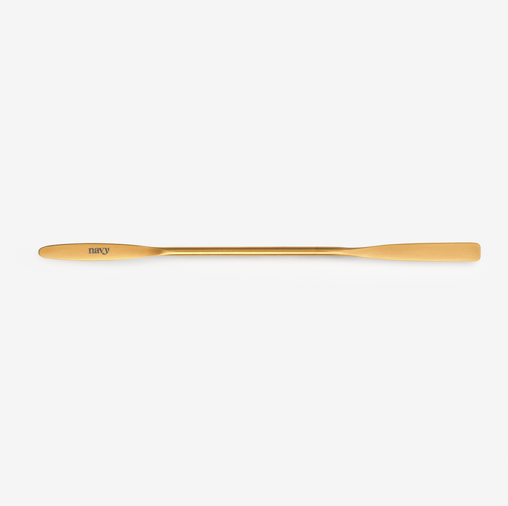 A gold-colored Iris mixing spatula designed for beauty treatments.