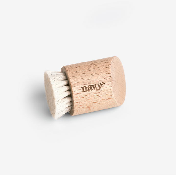 A wooden nail dust brush with curved handle and white bristles, branded with the name 'Navy'.